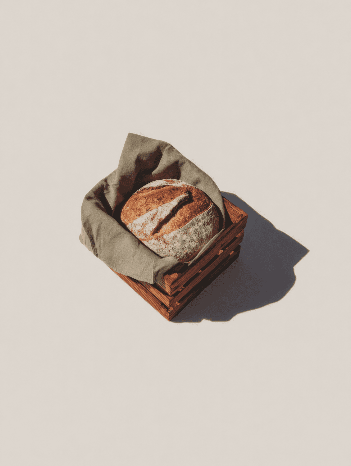 Freshly baked artisan loaves resting in a wooden crate on a linen cloth
